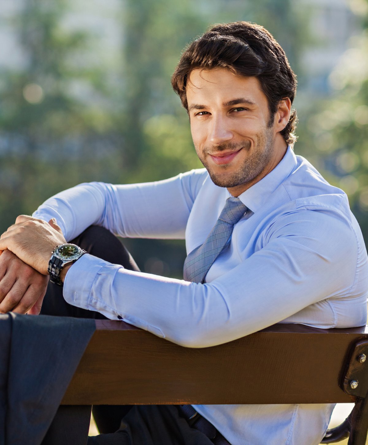 Grand Rapids hair loss treatment patient model sitting on a park bench in a blue sweater